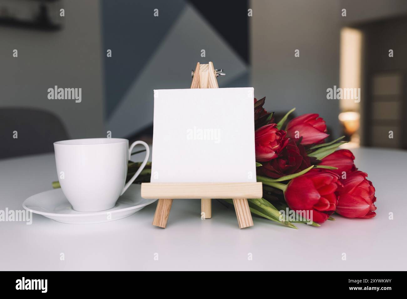 Bouquet di tulipani rossi sul tavolo e tazza di caffè bianco, cornice bianca vuota. Concetto per biglietto d'auguri. Concetto di giorno delle madri, giorno internazionale delle donne co Foto Stock