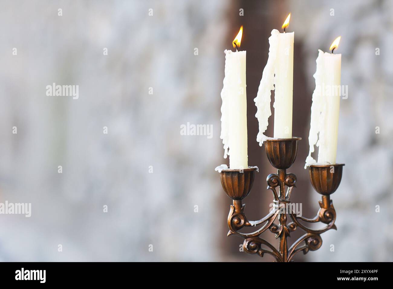 Candelabro con tre candele sul grigio Sfondo blured Foto Stock