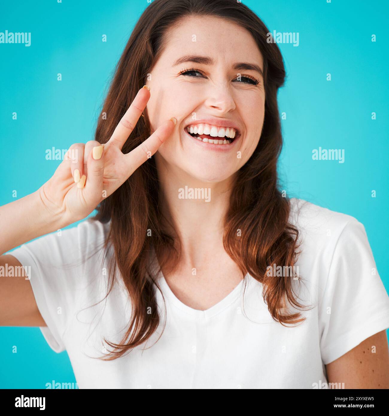 Donna sicura di sé e ritratto con segno di pace in studio per sostegno, positività e gentilezza emoji. Persona femminile, sorriso e felice con V gesto per Foto Stock