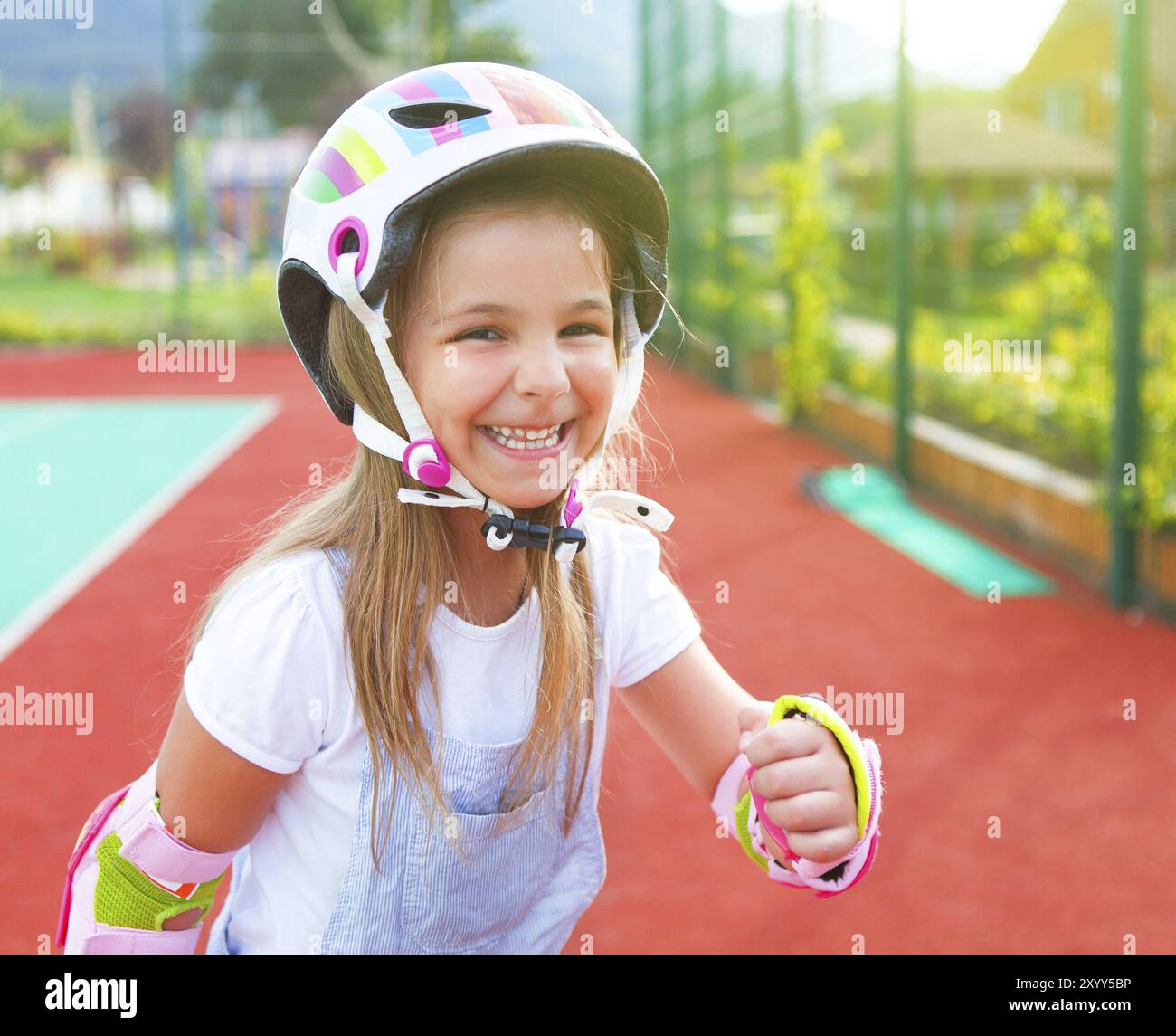 Poco sorridente ragazza in pattini a rotelle sul parco giochi Foto Stock