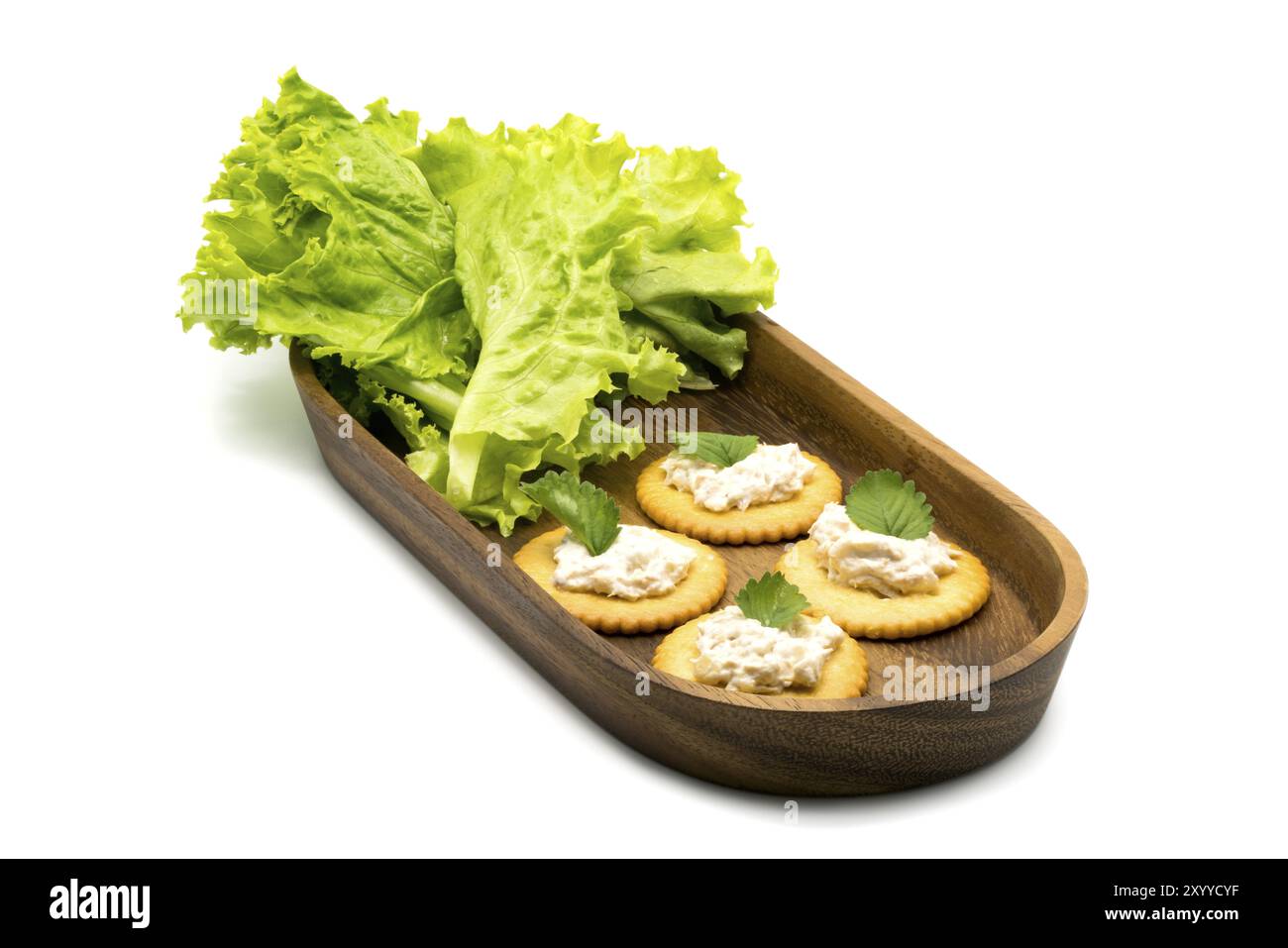 Round crackers con diffusione di tonno e verdure in vassoio di legno su sfondo bianco Foto Stock