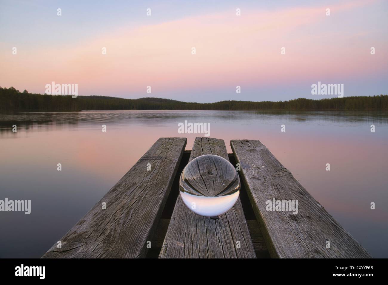 Palla di vetro su un molo di legno presso un lago svedese all'ora serale. Foto della natura dalla Scandinavia Foto Stock