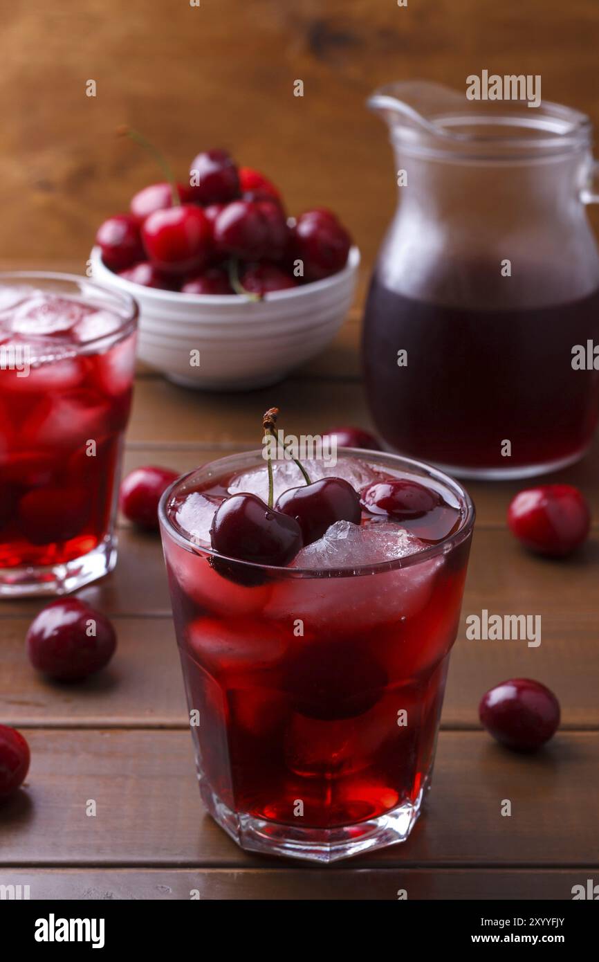 Primo piano di succo fresco con ciliegie dolci e ghiaccio su fondo di legno Foto Stock