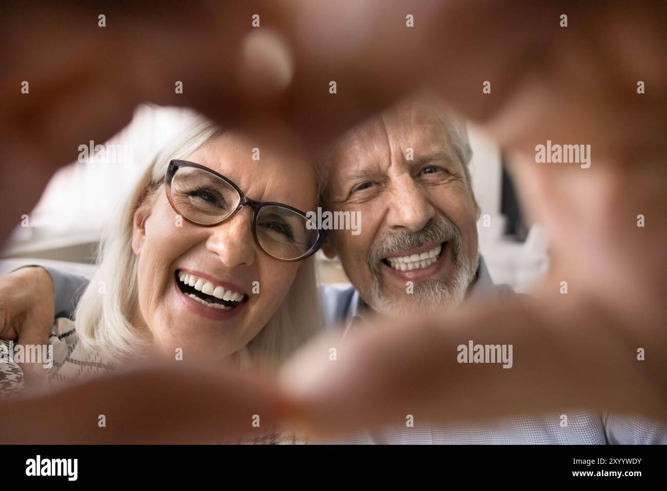 Felice coppia più anziana che mostra il simbolo dell'amore con le dita unite Foto Stock