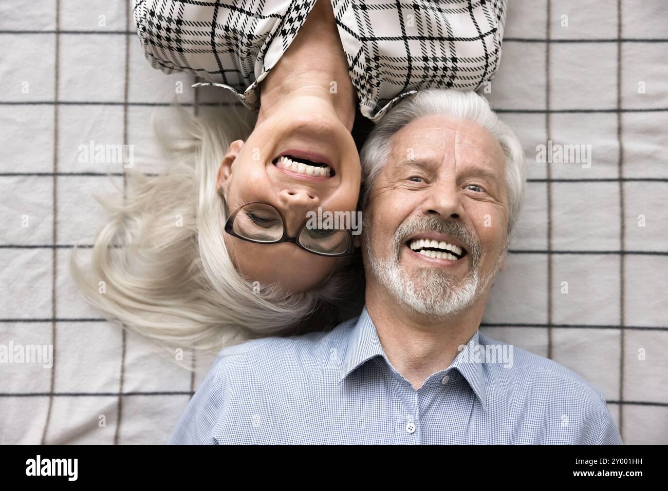 Allegra coppia sposata matura sdraiata su lenzuola a scacchi Foto Stock