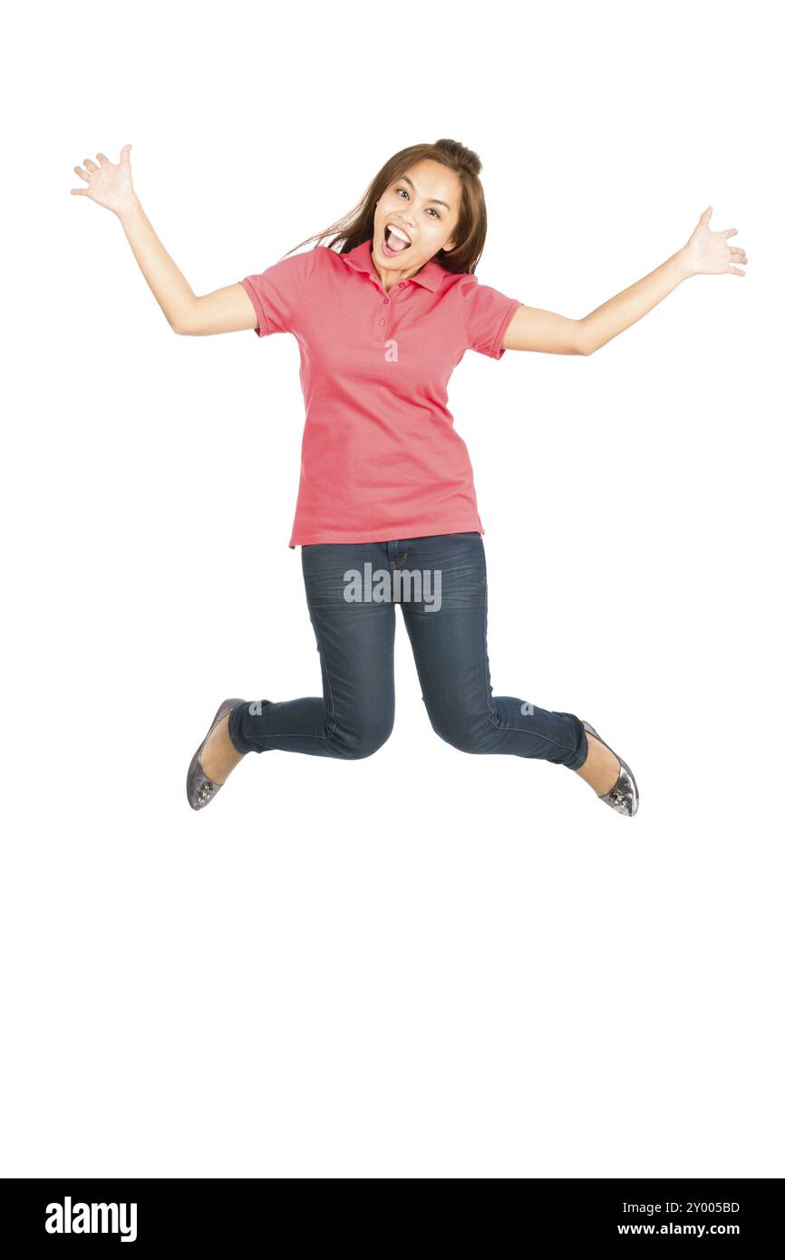 Donna asiatica carina in abiti casual, che salta in aria con un sorriso esagerato, braccia e gambe allungate, mostrando un'estrema felicità, estatica, o Foto Stock