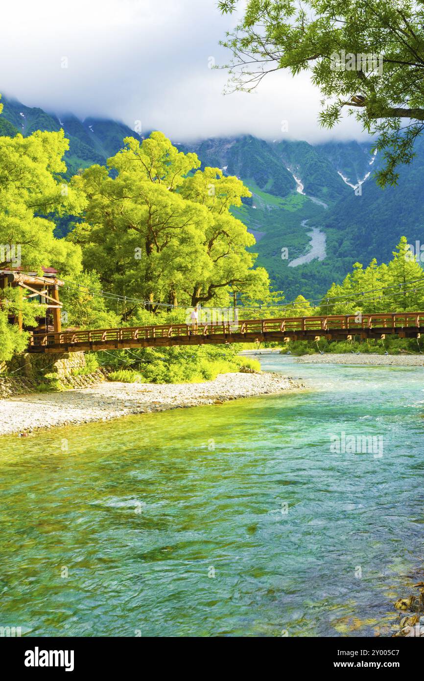 Uomo che attraversa il ponte Kappa con lo sfondo del monte Hotaka durante la mattina di sole a Kamikochi nelle Alpi giapponesi, prefettura di Nagano, Giappone. Ve Foto Stock