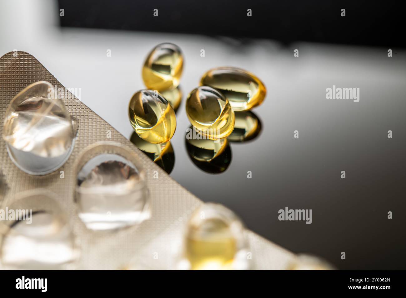 Una disposizione di capsule gialle trasparenti, tra cui vitamina D e integratori di olio di pesce omega-3, che riflettono i benefici per la salute e il valore nutrizionale Foto Stock