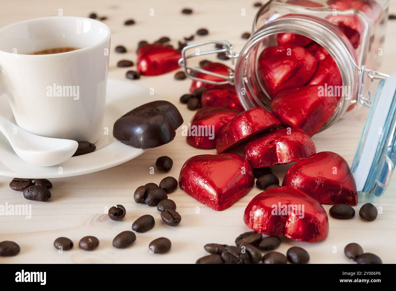 Rosso Cuori di cioccolato in un vasetto di vetro e un caffè espresso con i chicchi di caffè in una tabella Foto Stock