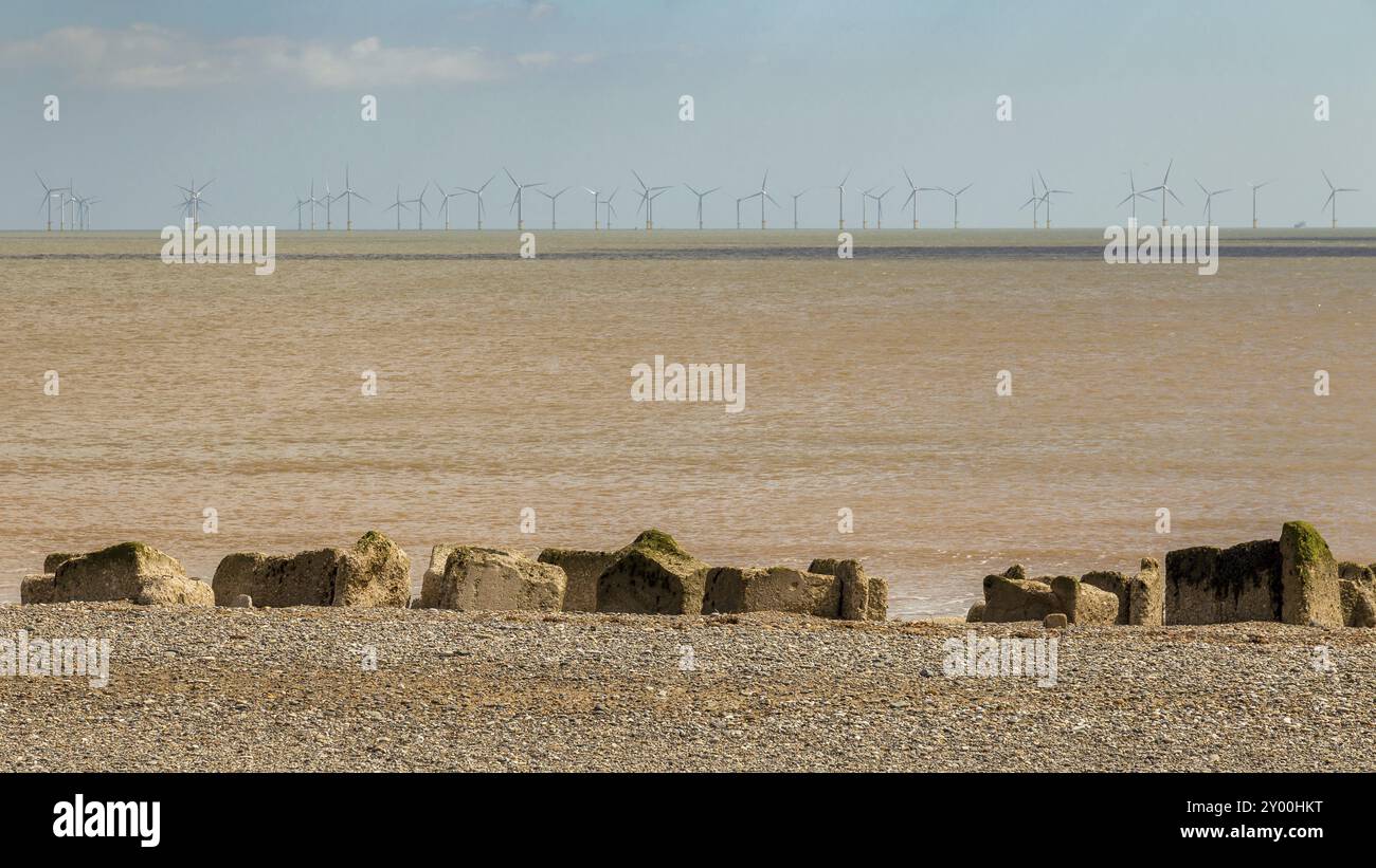 Costa del Mare del Nord, sulla spiaggia di ciottoli e sassi, e turbina eolica, vicino Kilnsea, East Riding of Yorkshire, Regno Unito Foto Stock