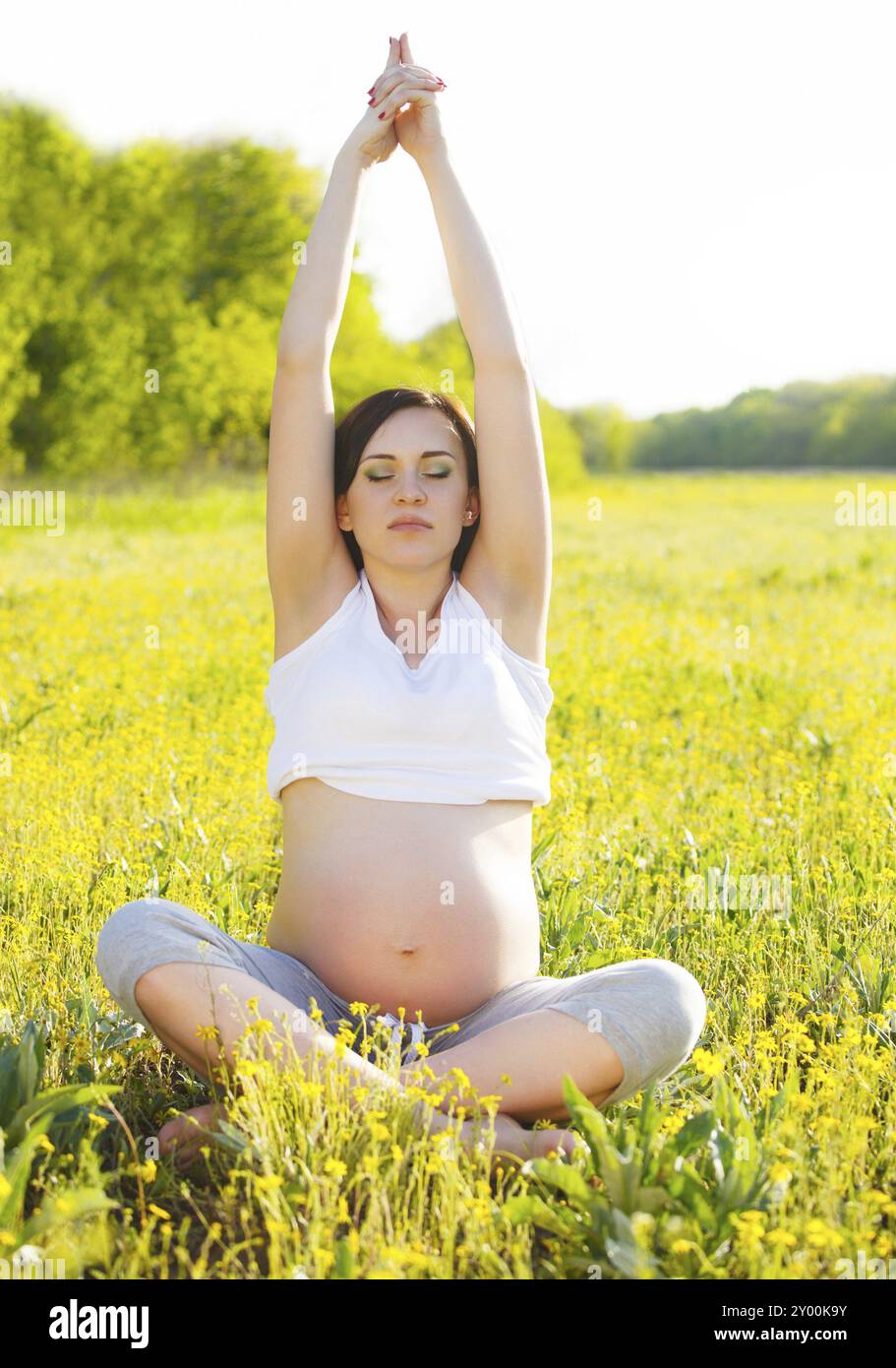 Un sano donna incinta fare yoga nella natura all'esterno. Tempo di primavera Foto Stock