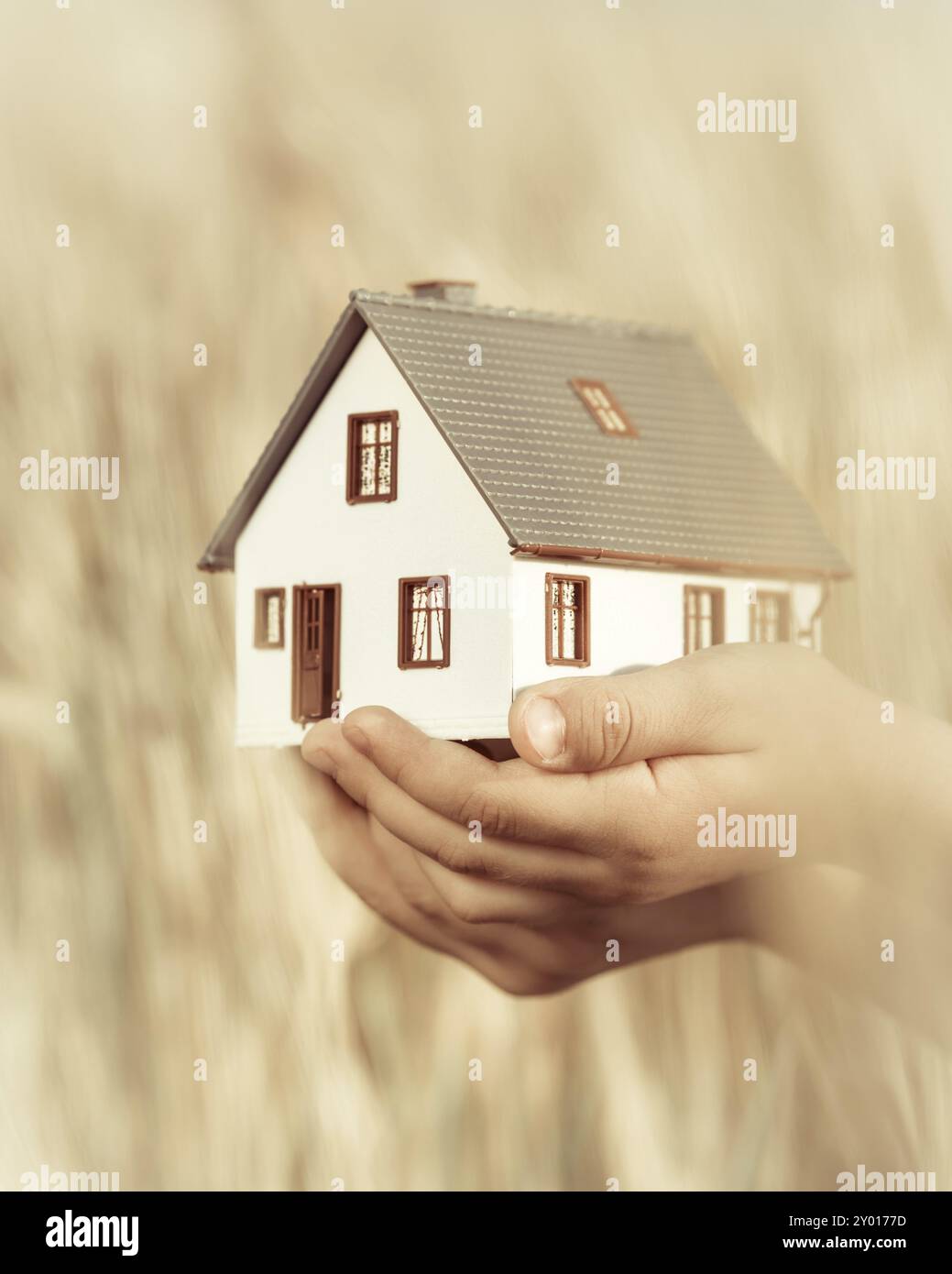 Casa nelle mani dei bambini su sfondo giallo autunnale. Concetto immobiliare Foto Stock