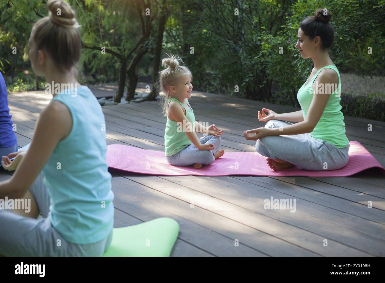 Gruppo di madri e figlie fare esercizio di praticare yoga all'esterno. Uno stile di vita sano Foto Stock