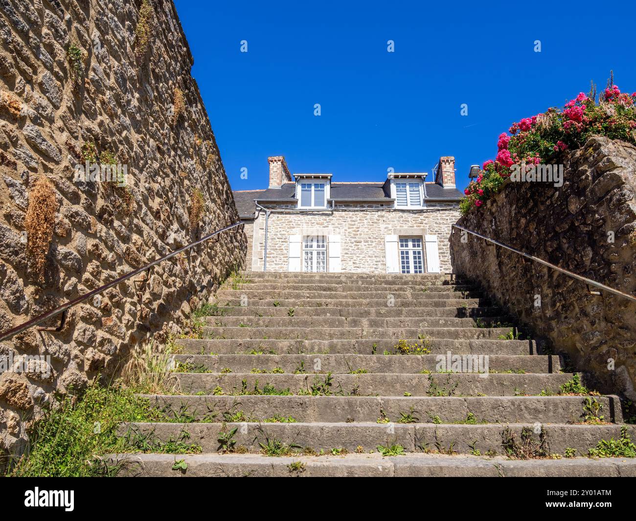 Scalini in pietra a Dinan, Bretagna, che conducono ad un'affascinante casa bretone in pietra sotto il cielo azzurro e soleggiato. Foto Stock