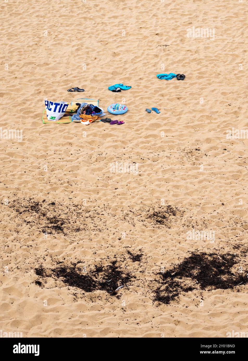 Saint Malo, Francia - 20 luglio 2024: Spiaggia sabbiosa con asciugamano colorato, borsa, abbigliamento e detriti di alghe. Foto Stock