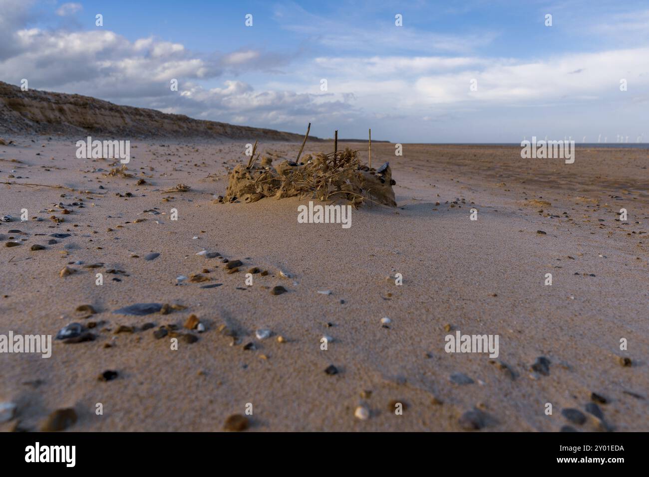 Un castello di sabbia sulla spiaggia di Great Yarmouth, Norfolk, Inghilterra, Regno Unito, con alcune turbine eoliche del parco eolico Scroby Sands nel Mare del Nord Foto Stock