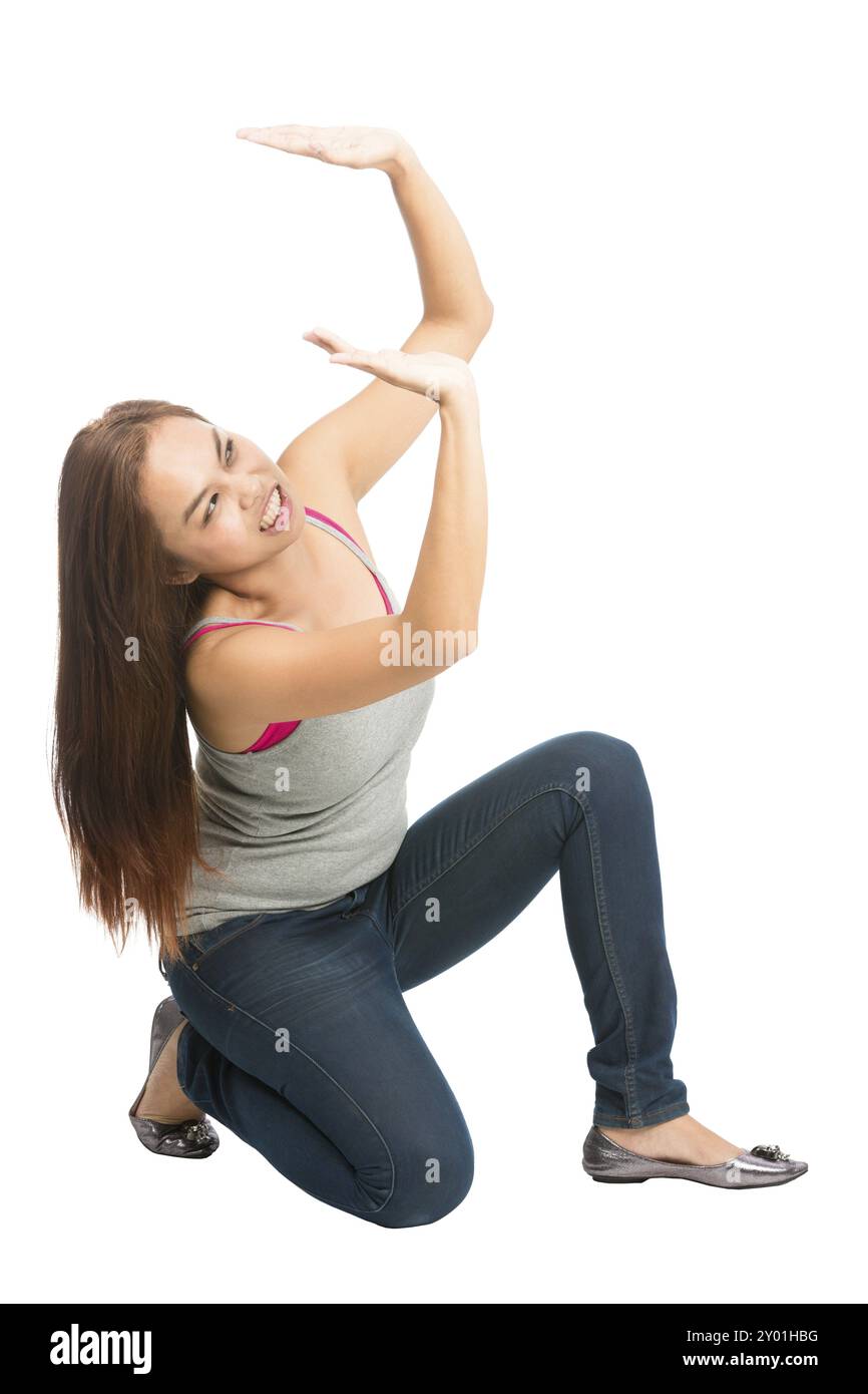 Donna asiatica in difficoltà inginocchiata sotto peso in abiti casual, le braccia estendevano il sostegno, venivano schiacciate, spingendo contro la caduta di placemen di prodotti Foto Stock