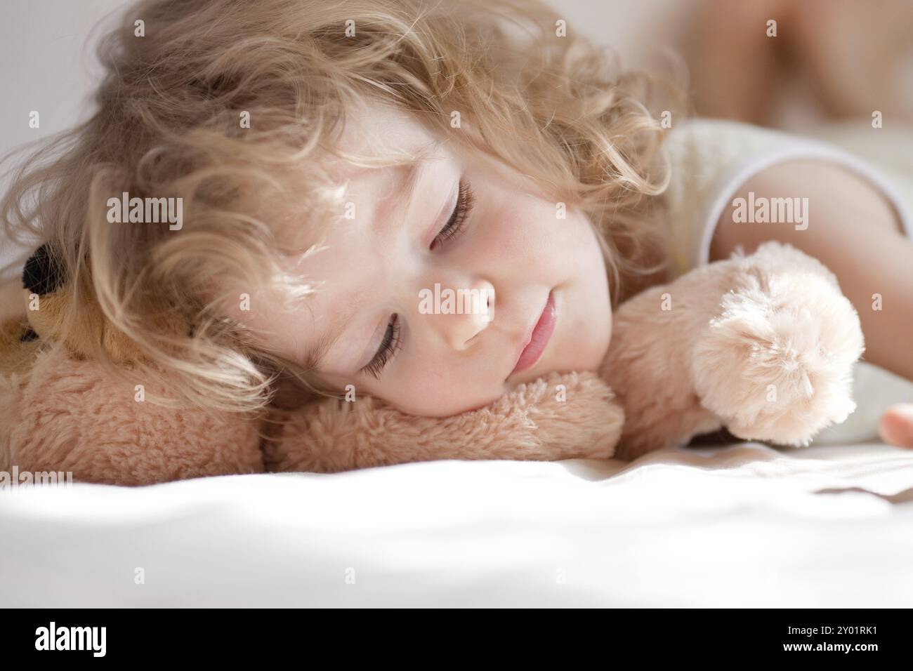 Bambino che dorme nel letto con il teddy Foto Stock