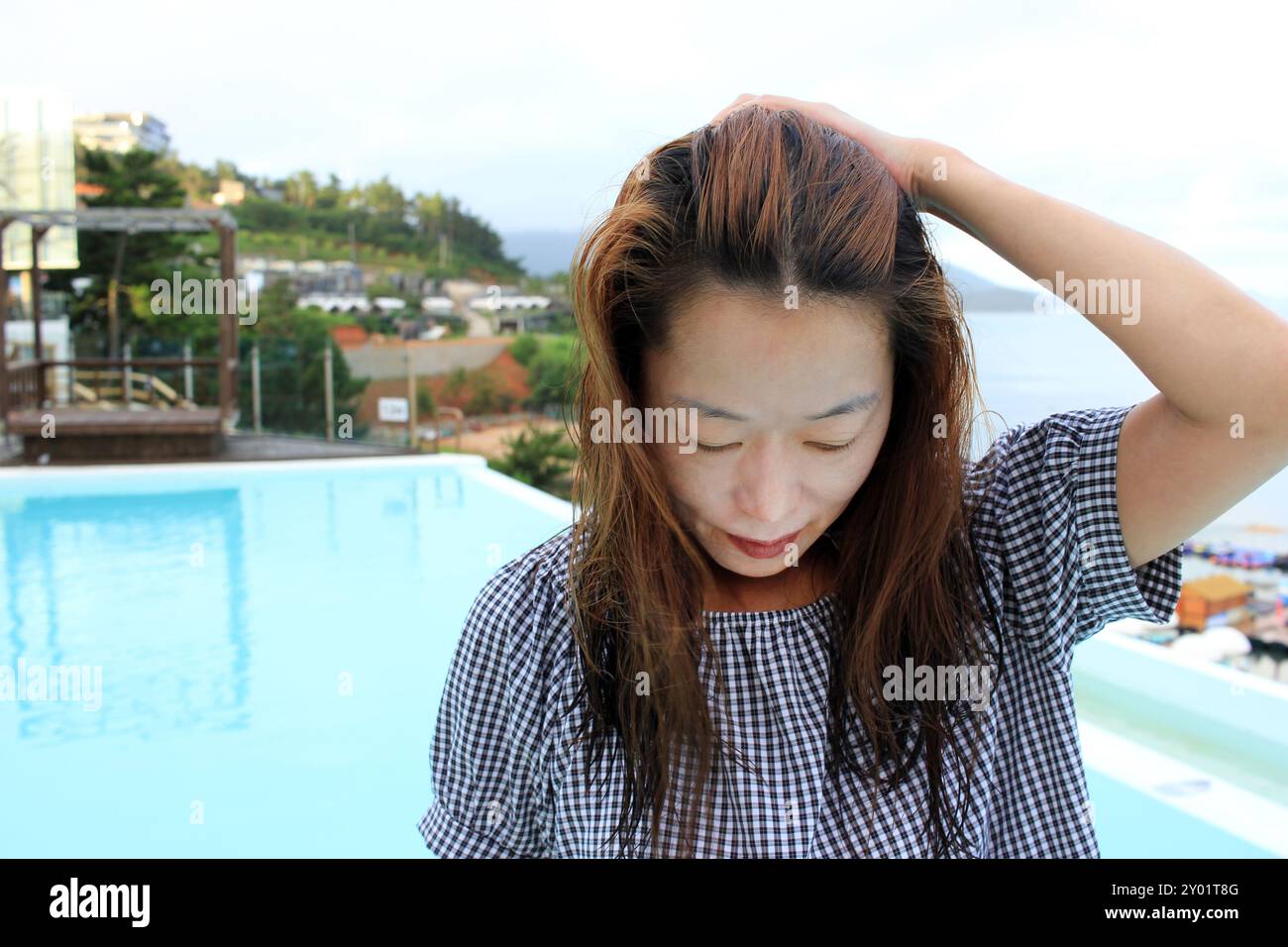 Dolsan-eup, Yeosu-si, Corea del Sud - 26 luglio 2024: Giovane donna che guarda l'alba in un resort con piscina affacciata sul mare di Yeosu Foto Stock