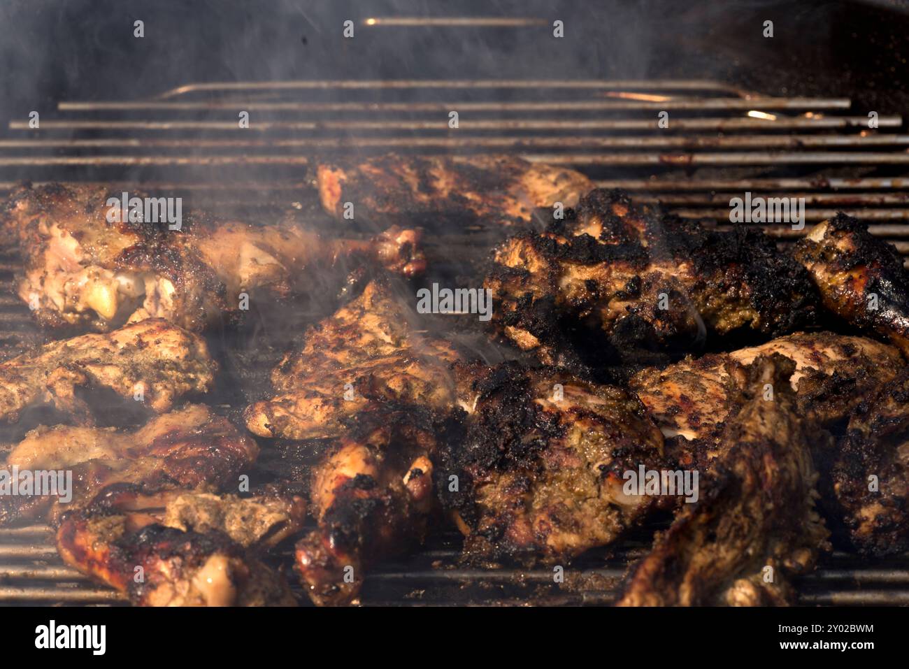 Primo piano di pezzi di pollo grigliati su un barbecue affumicato, perfetto per i pasti estivi e contenuti a tema barbecue. Foto Stock