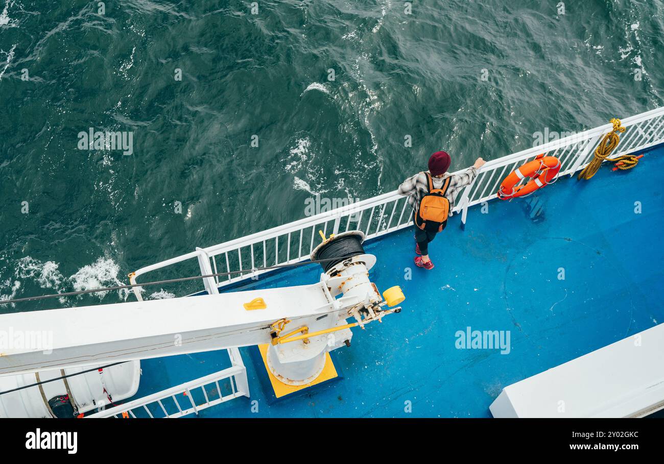 Donna con zaino che gode dei paesaggi del Mare del Nord sul traghetto norvegese durante il viaggio dalla Danimarca. La scena cattura l'essenza del viaggio rilassato, l'esplorazione i Foto Stock