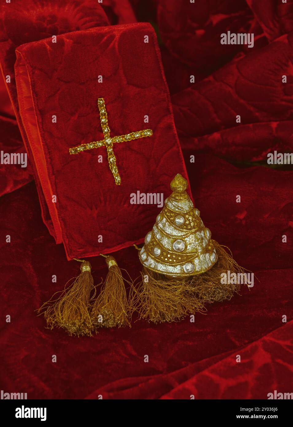 Albero di Natale bianco e oro su tappezzeria di velluto rosso con nappine dorate, sullo sfondo è presente una croce con filo d'oro che simboleggia la religione cristiana. Foto Stock
