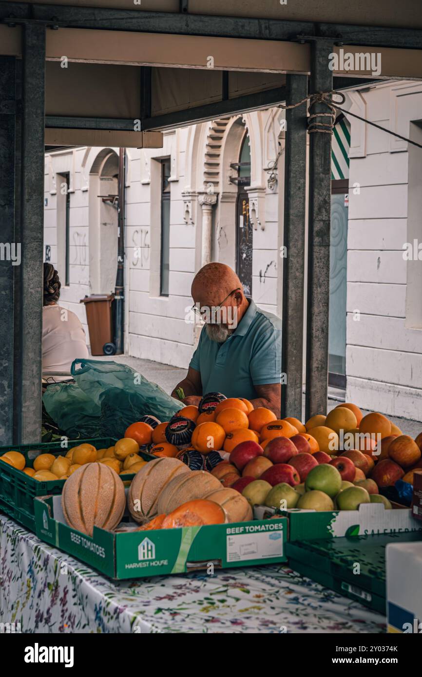 Rijeka Croazia 25.06.24 un uomo anziano è seduto e prepara verdi per la vendita Foto Stock