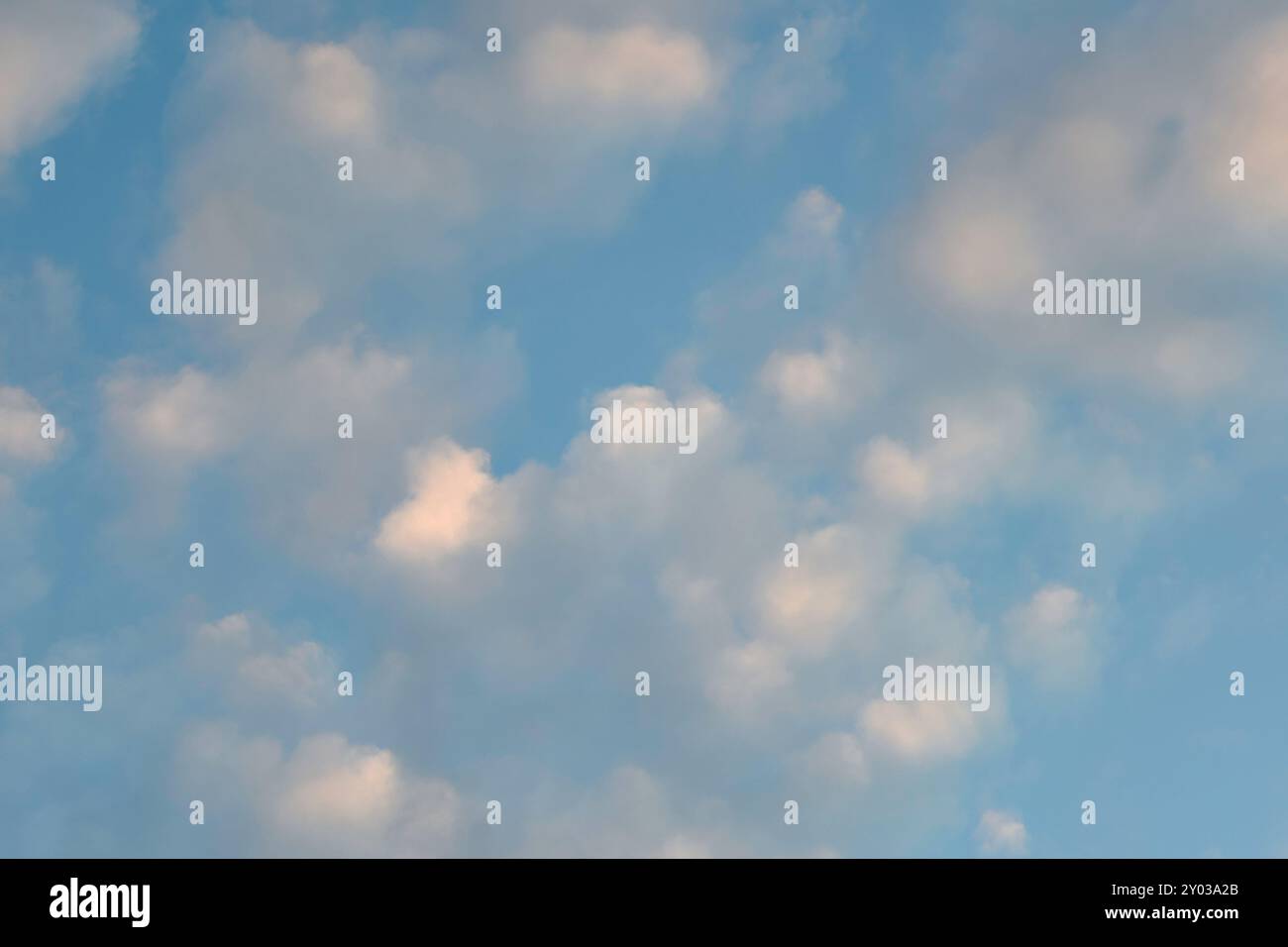 Lo sfondo della carta da parati di cumulus nuvole su un cielo blu durante l'illuminazione del crepuscolo. Foto Stock