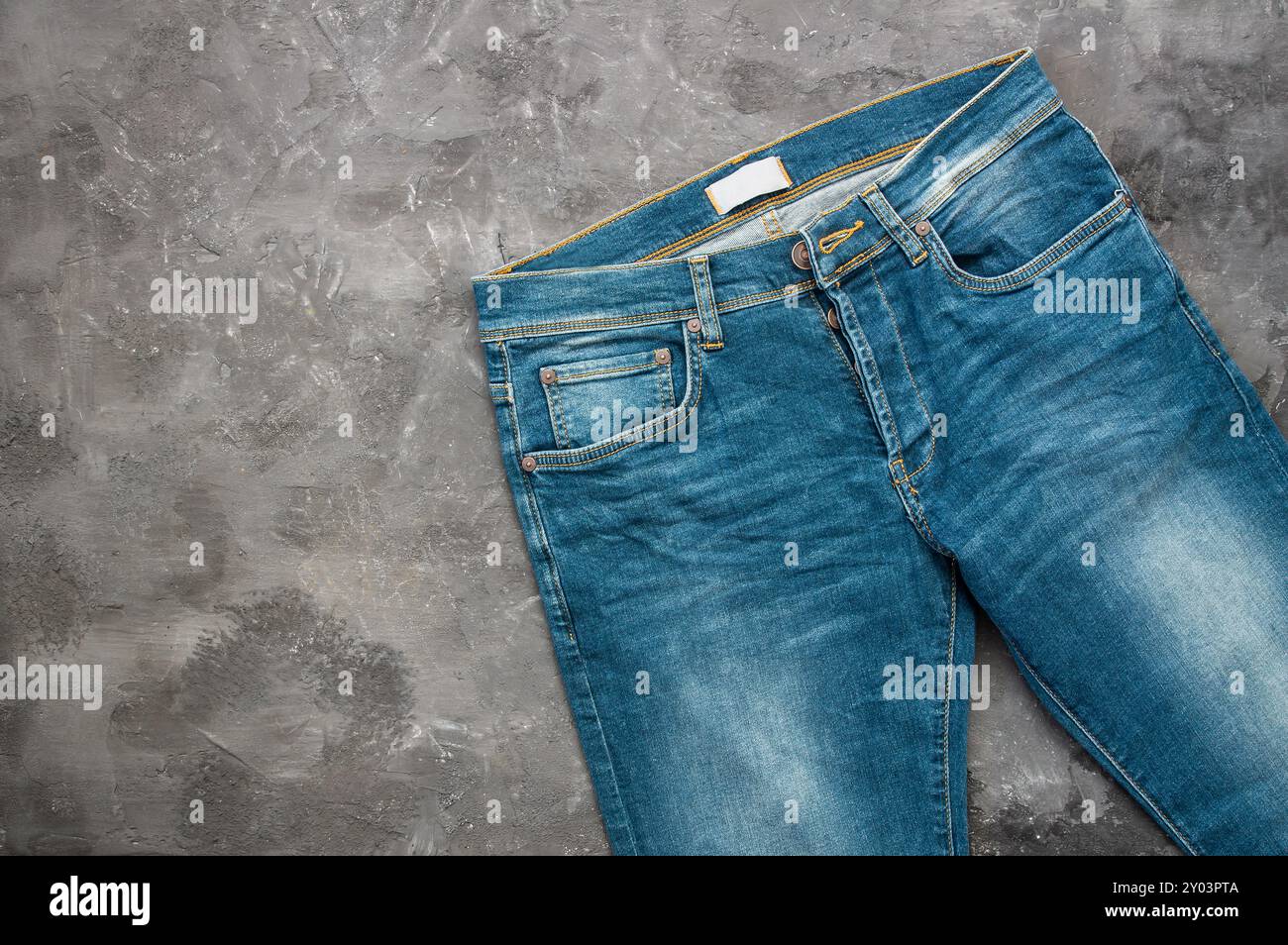 jeans blu singolo, pantaloni su fondo rustico in pietra, design alla moda Foto Stock