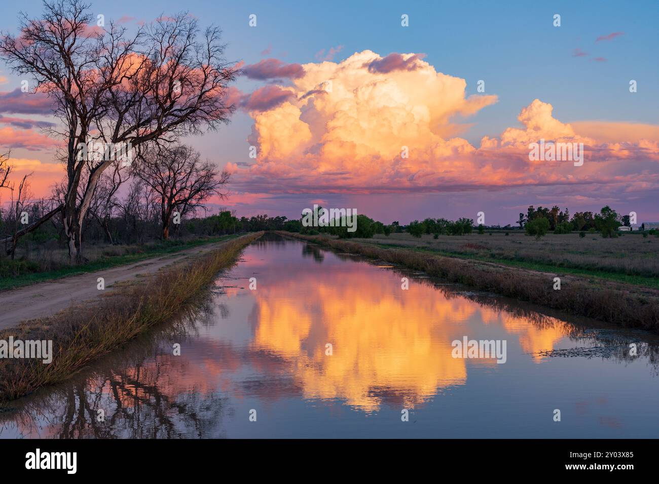 Una grande nube di tempesta colorata si riflette in un canale di irrigazione a St. George nel Queensland meridionale, Australia Foto Stock