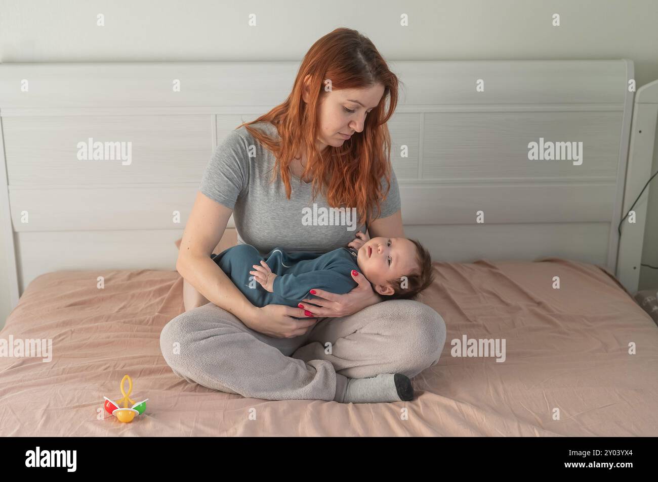 Donna con depressione post-partum seduta sul letto e in attesa di un figlio neonato. Foto Stock