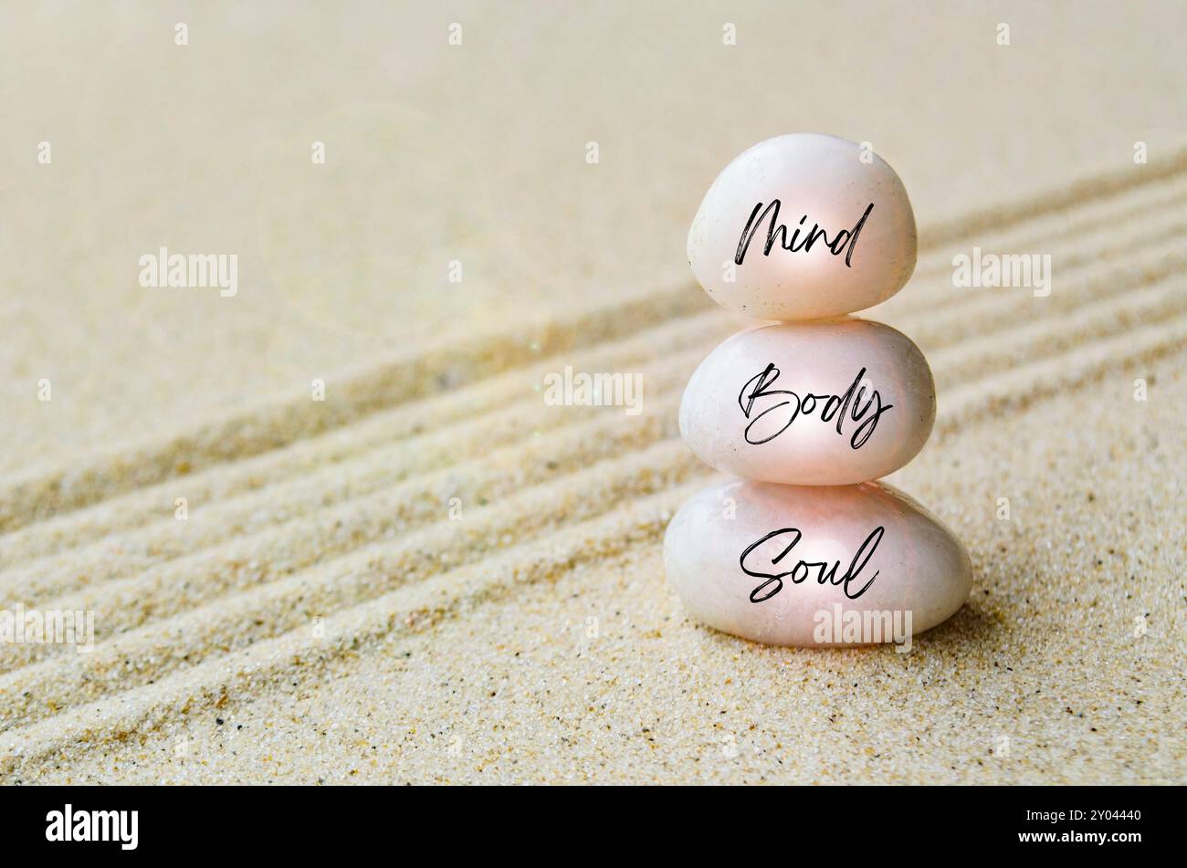 Testo Mind, Body and Spirit inciso su pietre zen bianche con fondo in foglia e sabbia. Concetto di pace e armonia. Foto Stock