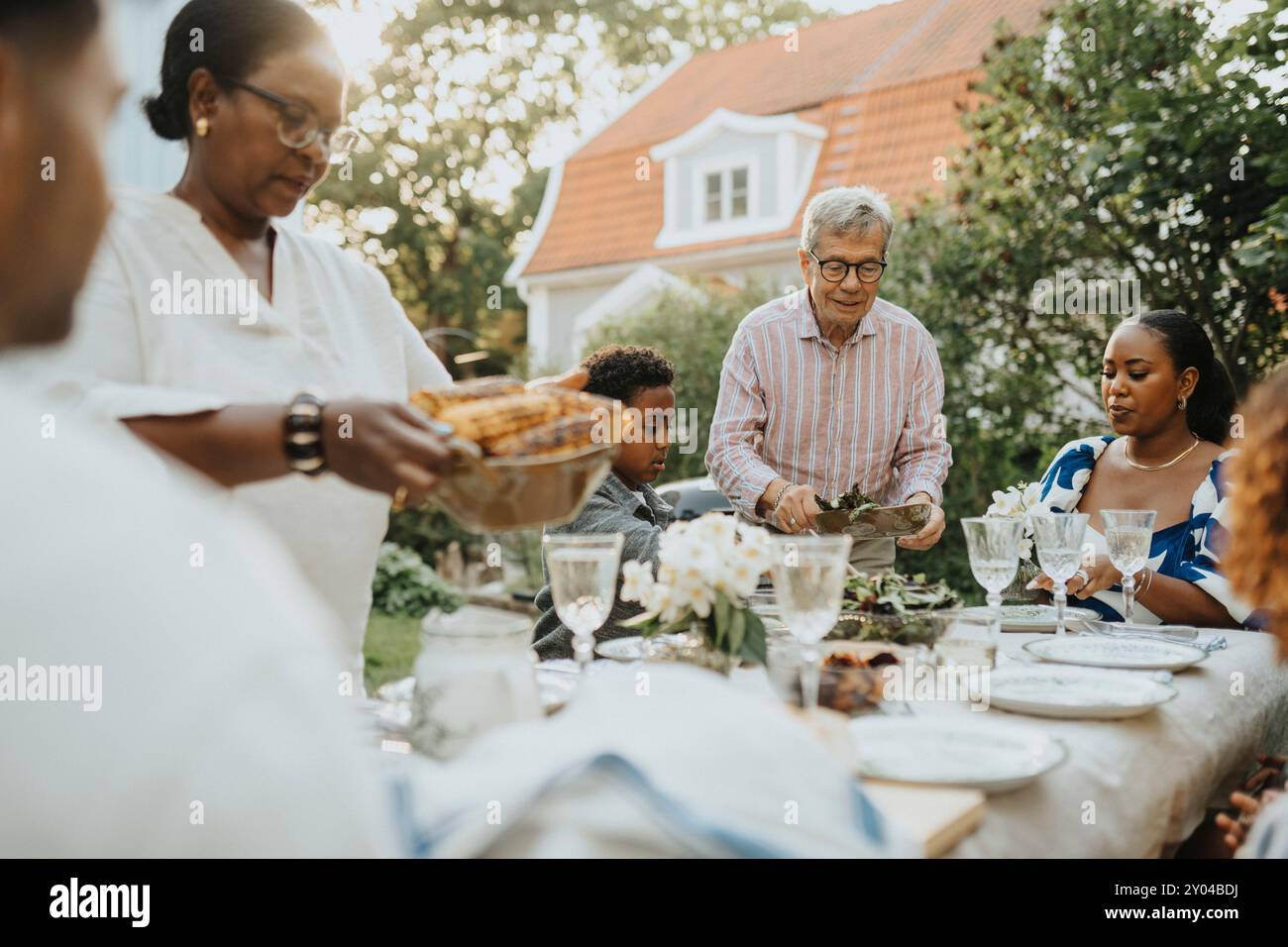I membri della famiglia maschi e femmine pranzano durante la riunione di famiglia alla festa in giardino Foto Stock