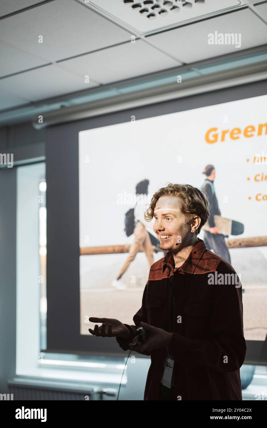 Giovane imprenditore sorridente che tiene una presentazione al centro conferenze durante il seminario Foto Stock