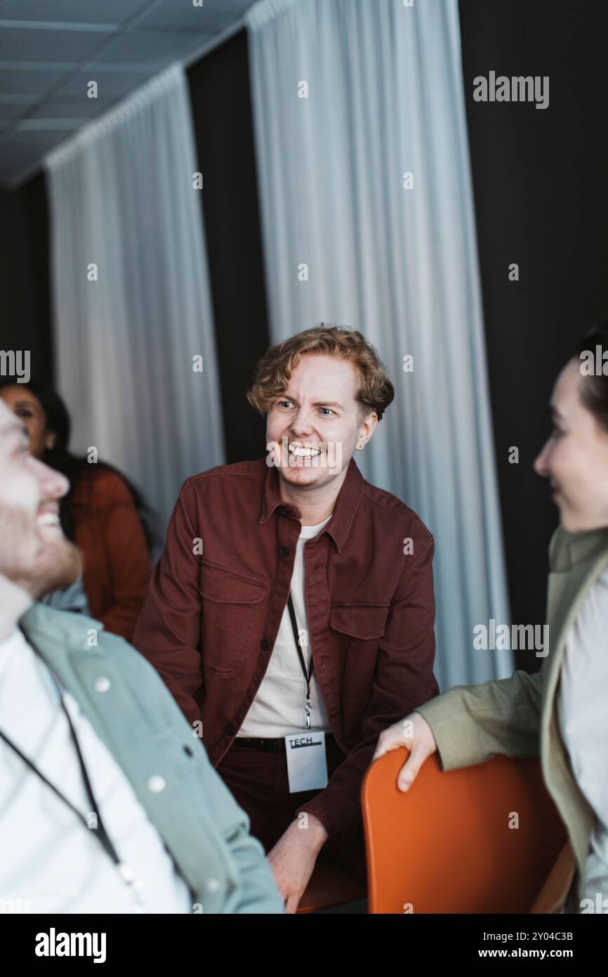 Un giovane imprenditore sorridente che parla con i delegati durante il seminario al centro congressi Foto Stock