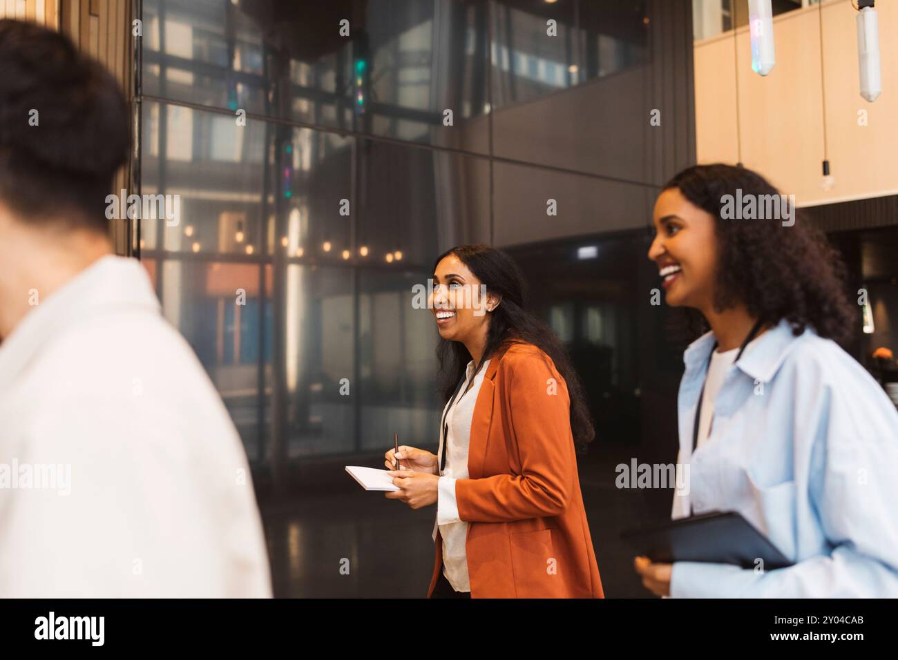 Donna d'affari sorridente che cammina con una delegata durante un seminario al centro convegni Foto Stock