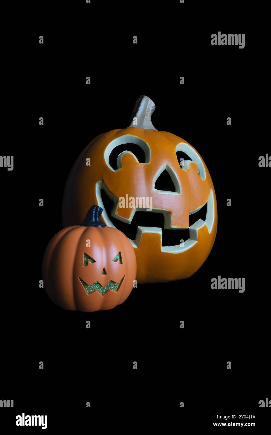 Questa immagine presenta due zucche di halloween scolpite, entrambe con facce sorridenti, isolate su uno sfondo nero. Foto Stock