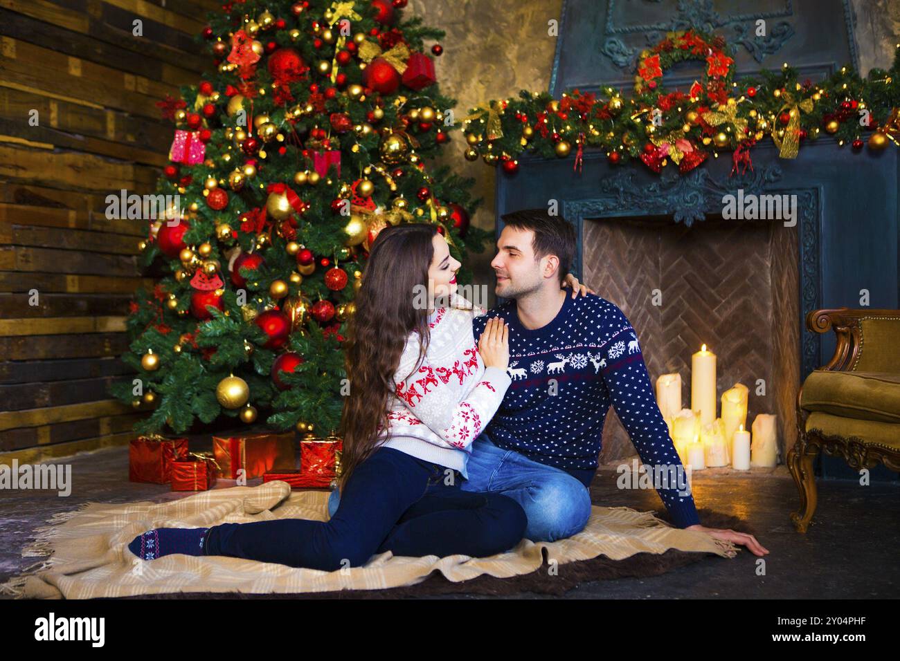 Giovane coppia vicino al caminetto per festeggiare il Natale. Concetto di amore e relazione Foto Stock