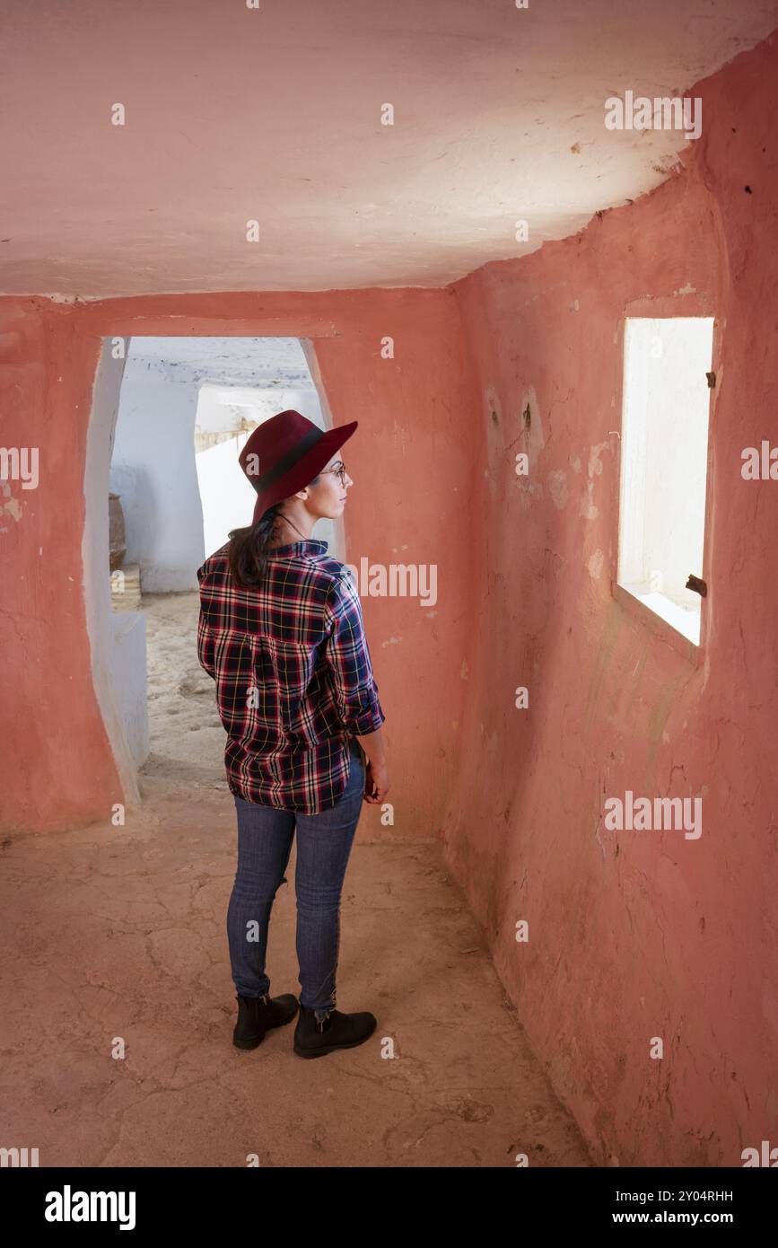 Donna che guarda la finestra all'interno delle grotte di Argueda con pareti rosa, in Spagna Foto Stock