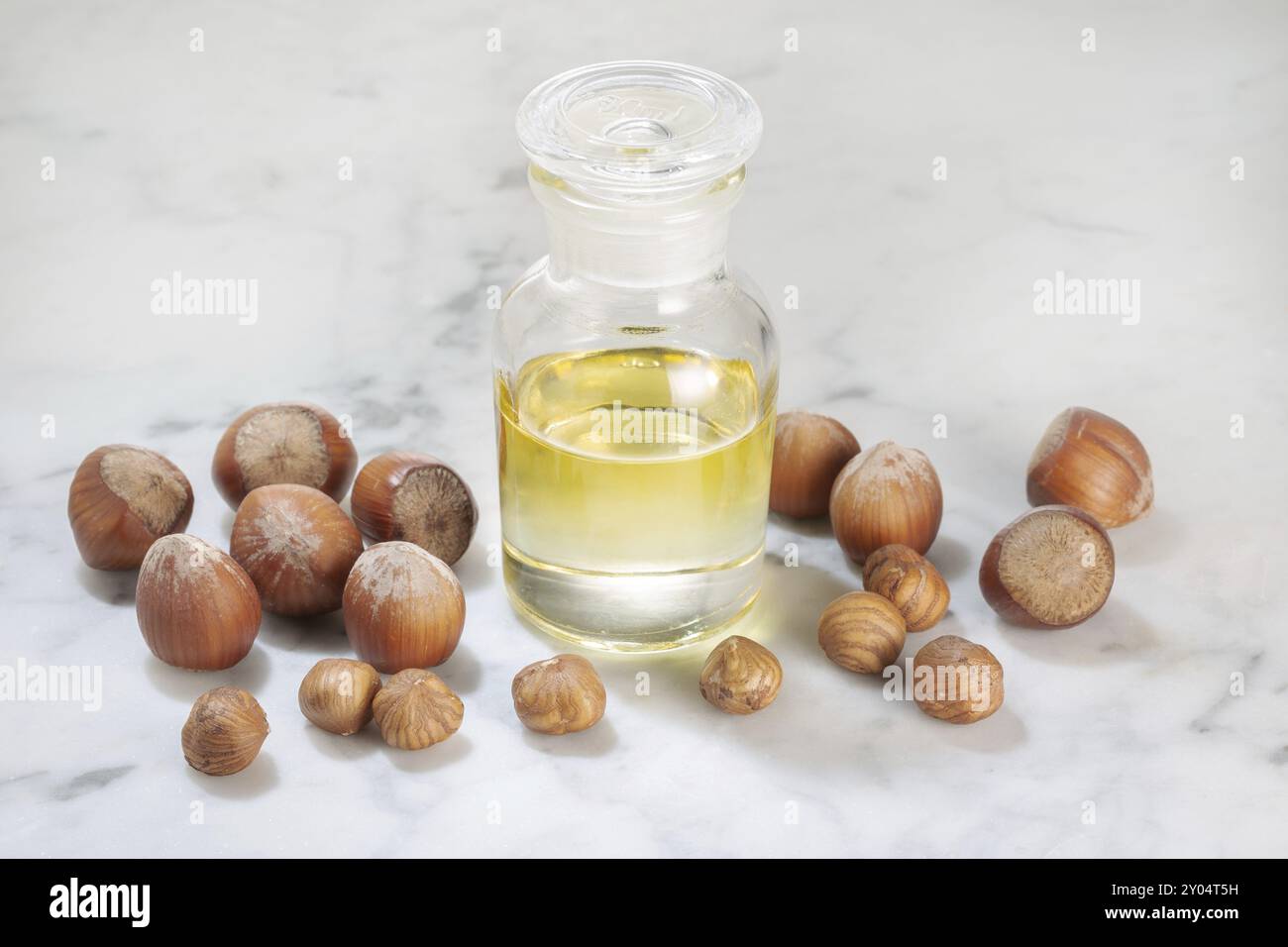 Olio di nocciola in bottiglia di vetro su tavolo di marmo. Olio per cure estetiche o di bellezza Foto Stock