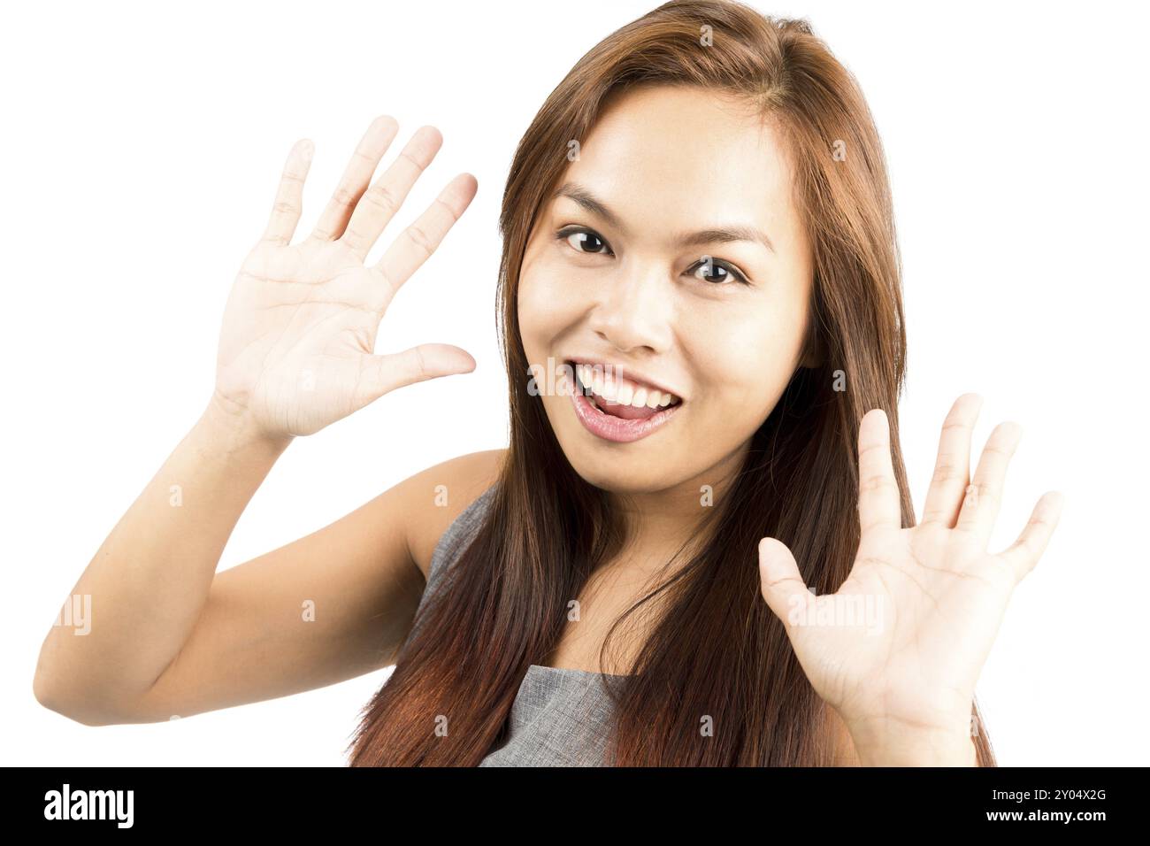 Ritratto di una ragazza asiatica carina e dall'aspetto carina in cima senza maniche con capelli marrone chiaro saluto con due mani che salutano o salutano in asiatiche non toccanti Foto Stock