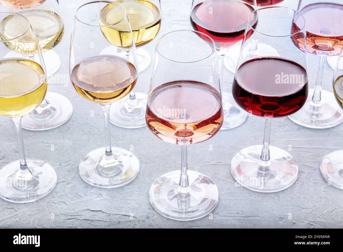 Bicchieri da vino ad una degustazione. Vino rosa, rosso e bianco, bevande al tavolo in una cantina. Un assortimento di vini di diversi colori Foto Stock