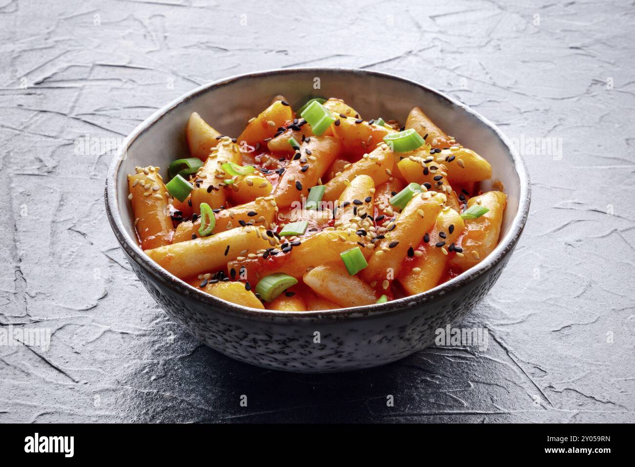 Tteokbokki o topokki, Street food coreano, torte di riso piccanti in salsa gochujang al peperoncino rosso, un piatto popolare, su sfondo nero Foto Stock