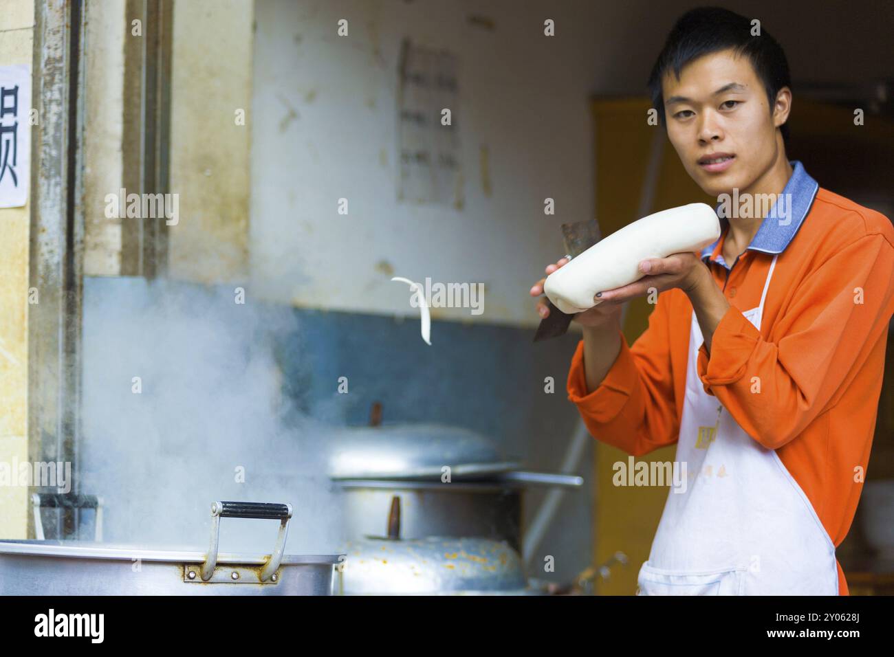 Lijiang, Cina, 21 settembre 2007: Un noodle crudo che vola a mezz'aria in una pentola di acqua bollente rasata da uno chef esperto da una palla di impasto a Lijiang Foto Stock