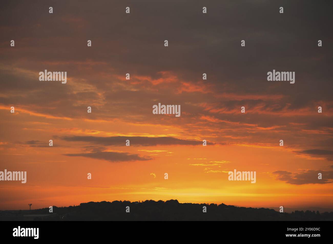 Cielo serale dopo il tramonto con nuvole rosse e la sagoma del settore privato di una piccola città Foto Stock