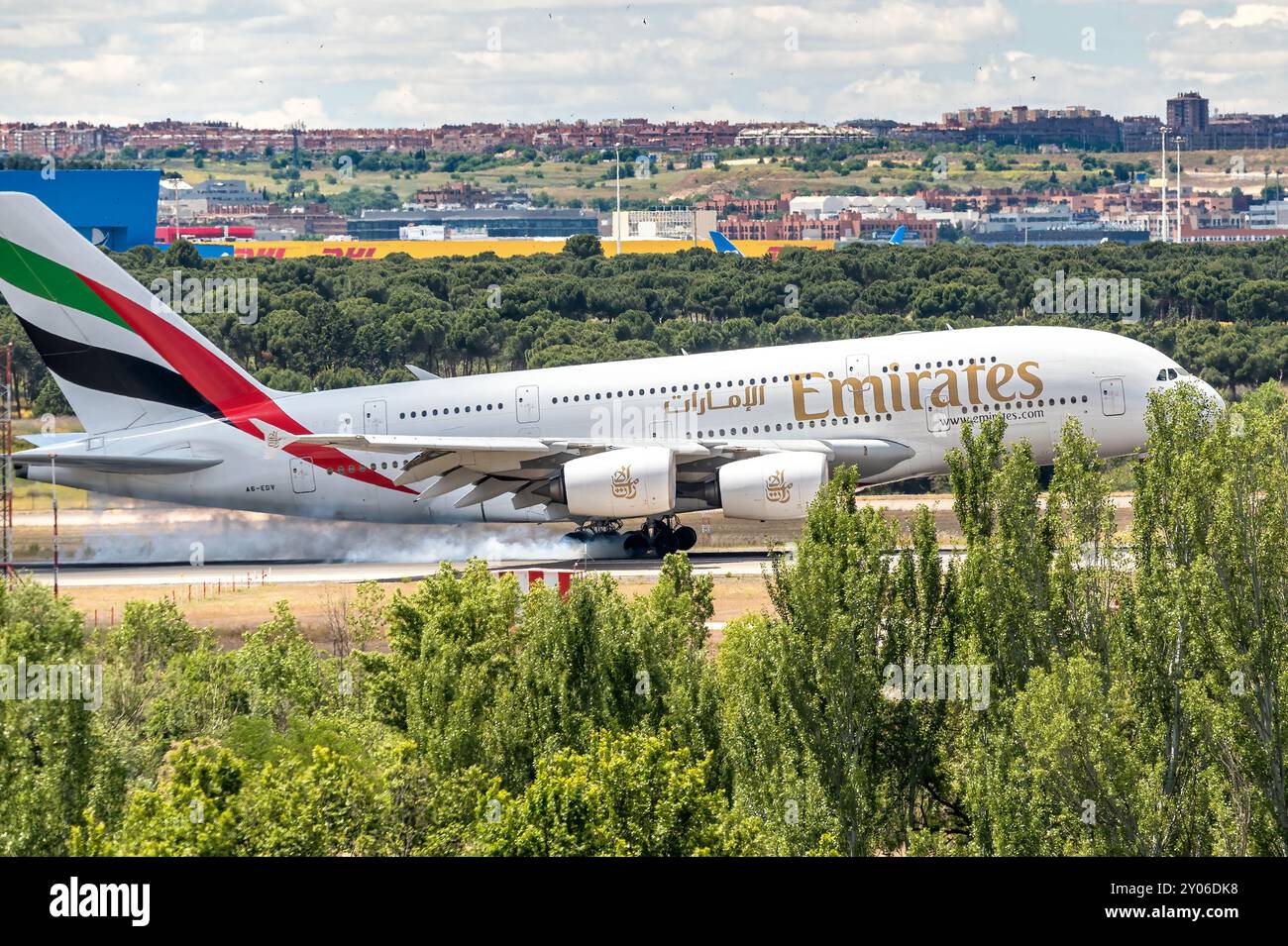 Madrid Spagna; 05-18-2024: Aereo della compagnia aerea Emirates e modello Airbus A380 atterrano sulla pista dietro alcuni alberi, causando un grande fumo durante la frenata Foto Stock