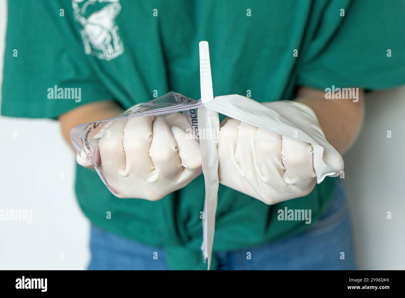 Donna Dottore in vestiti semplici apertura su imballaggio medico. Primo piano di mani femminili con guanti bianchi che aprono la confezione. Foto Stock