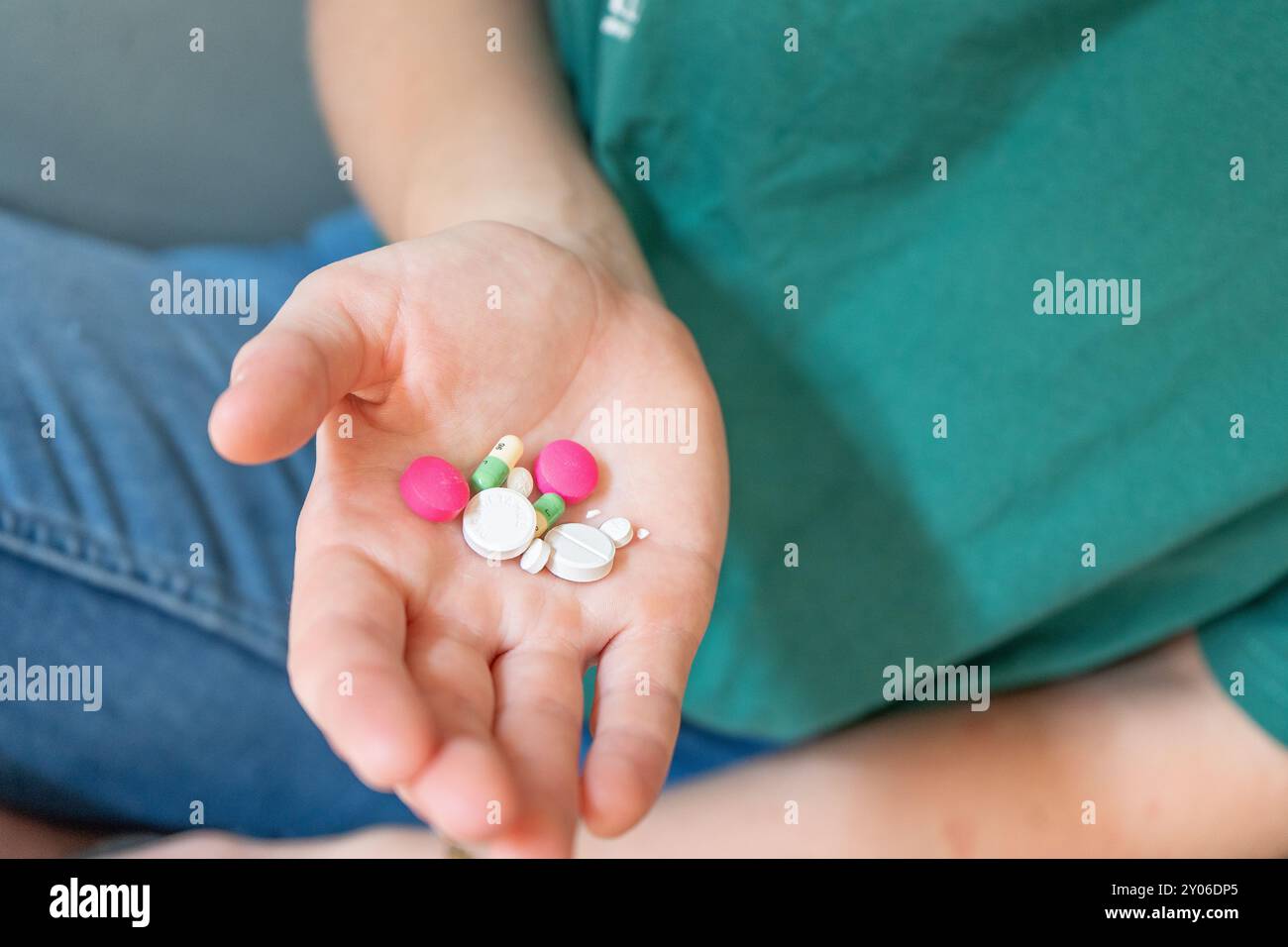 Ragazza che regge le pillole. Pillole di diversi colori in una mano. Scuotere le pillole dal flacone. Estrarre le pillole dalle bolle delle pillole. Foto Stock