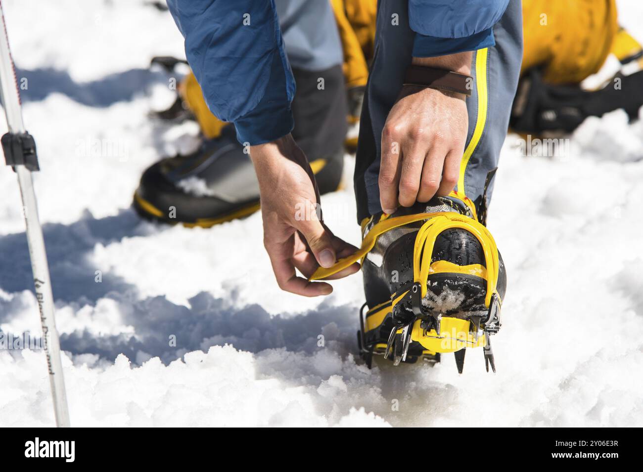 Un giovane escursionista si veste arrampicandosi sui Crampons con le scarpe da alpinismo per camminare su un ghiacciaio e sulla neve ghiacciata Foto Stock