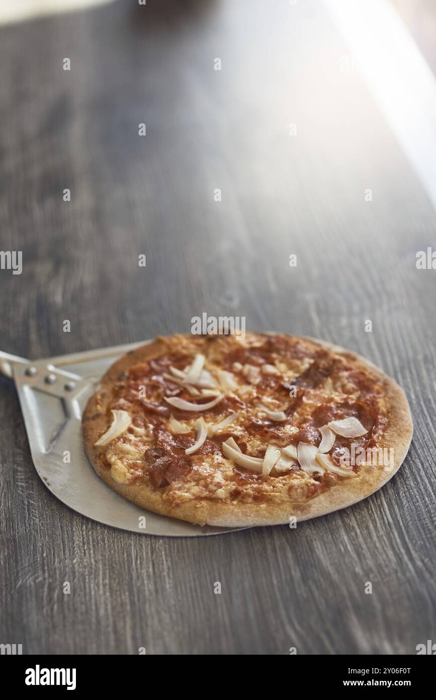 Appena cotto alla griglia di fiamma pizza italiana su una crosta croccante su un contatore di legno in una pizzeria con copia spazio sopra Foto Stock